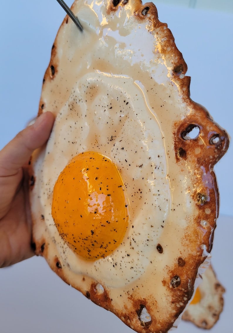 Fried egg hanging on a nail sculpture