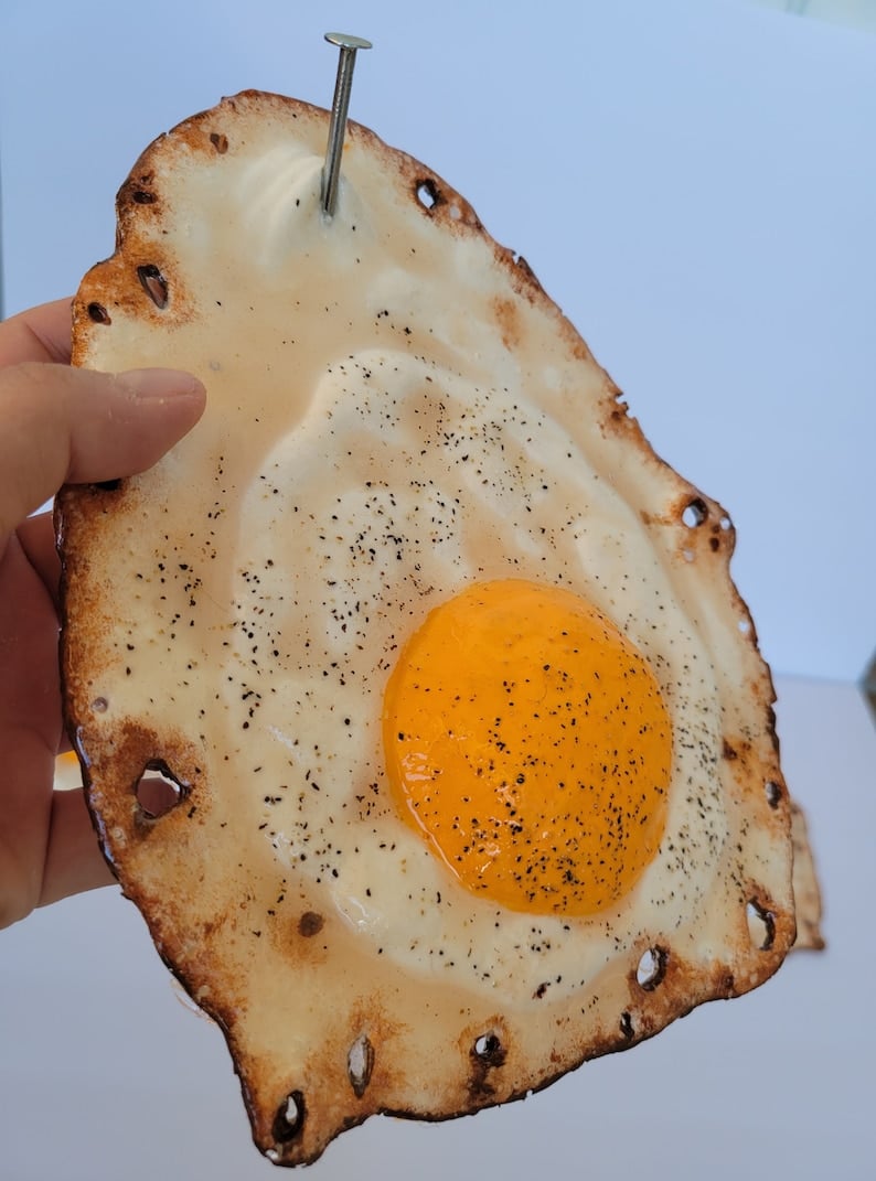 Fried egg hanging on a nail sculpture