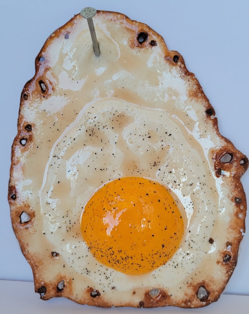 Fried egg hanging on a nail sculpture